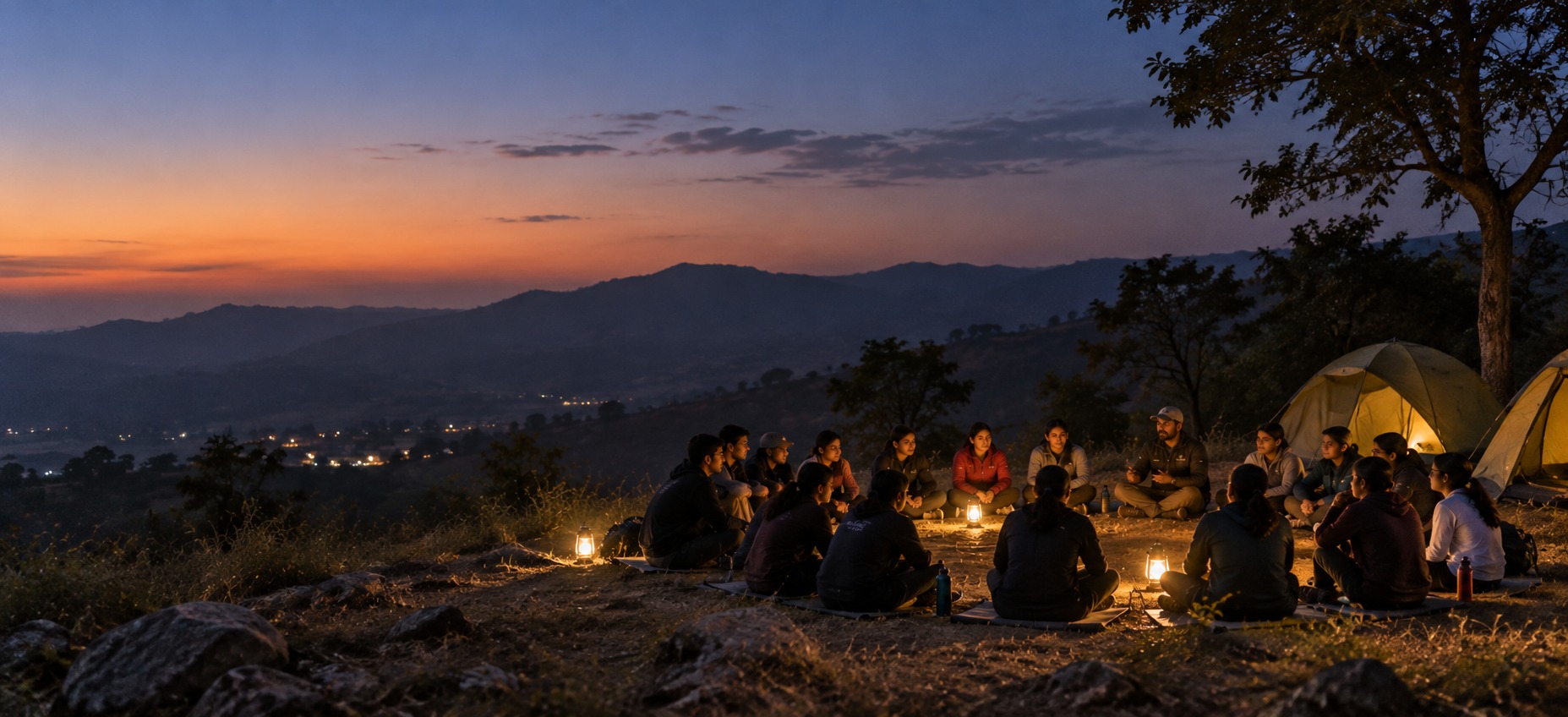 Students and an expedition leader in a circle at dusk, valley behind